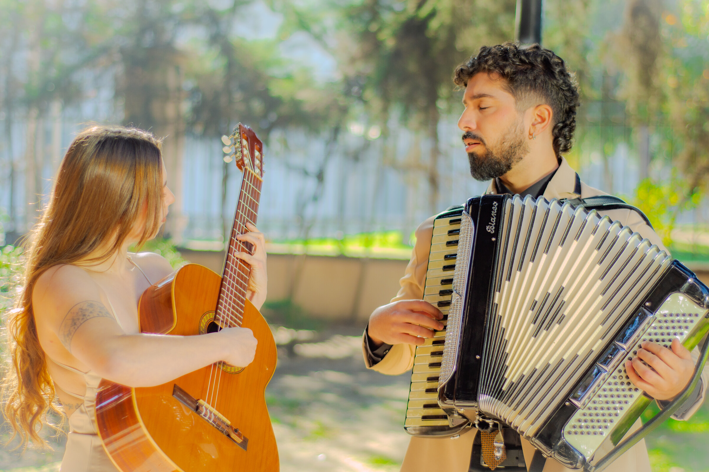 Dúo Amores de Chile tocando guitarra y acordeón con concentración en un jardín del Palacio Cousiño.