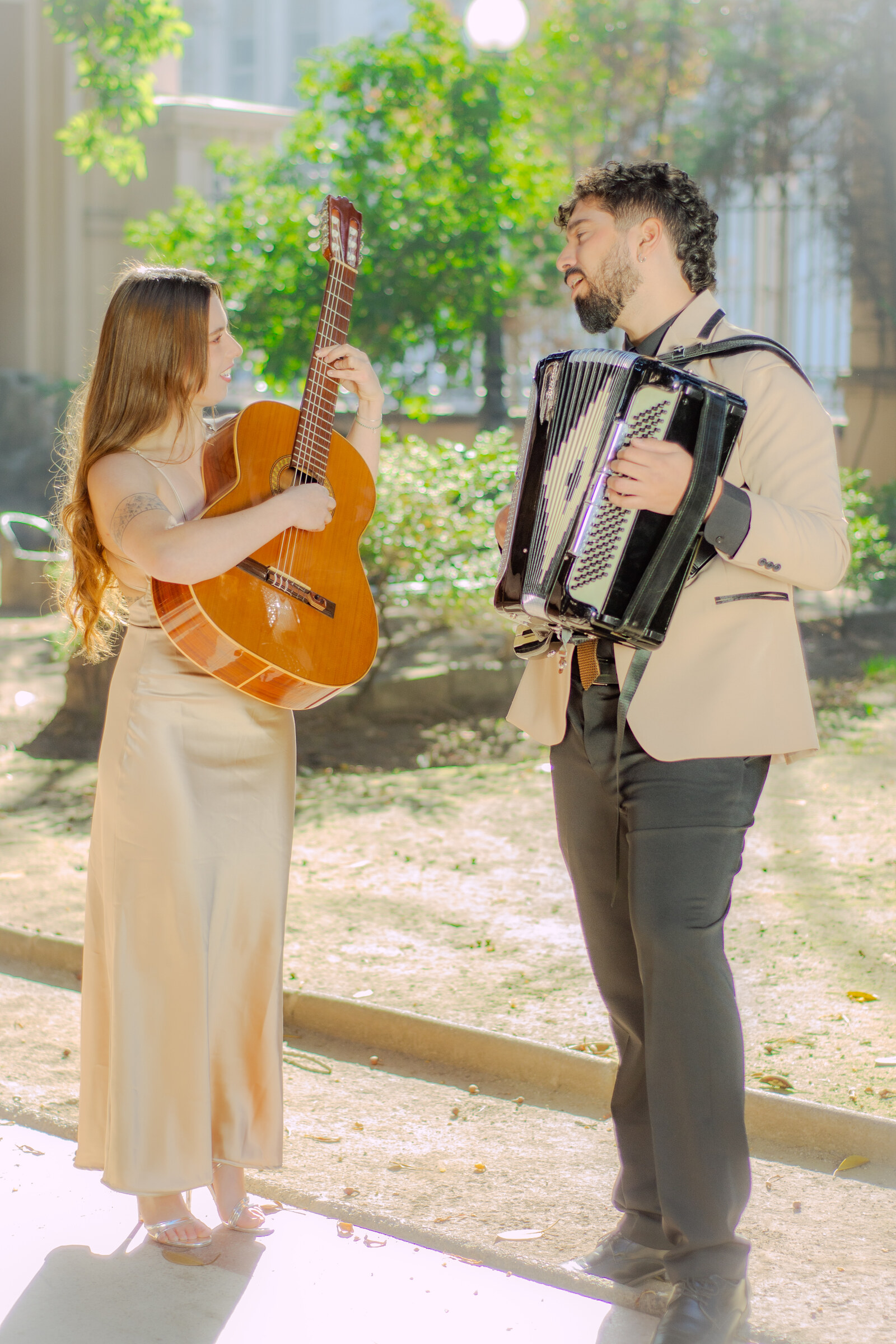 Dúo Amores de Chile tocando guitarra y acordeón con energía en un jardín soleado.