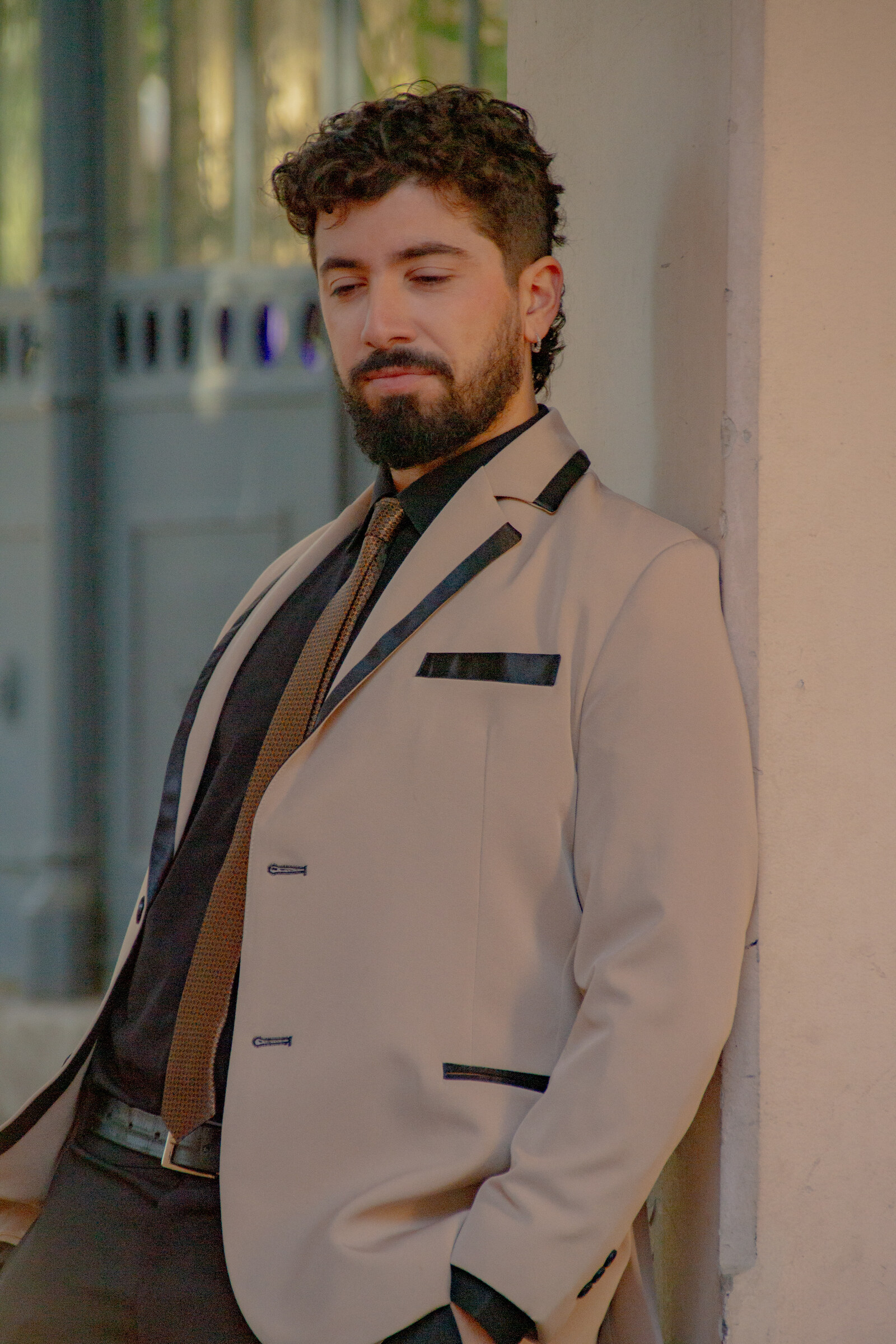 Músico del Dúo Amores de Chile posando pensativo con traje beige y corbata café en el Palacio Cousiño.