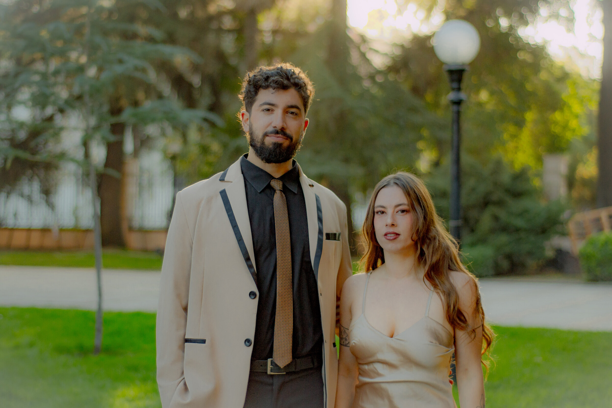 El Dúo Amores de Chile posa con elegancia en un parque, con luz cálida de atardecer.