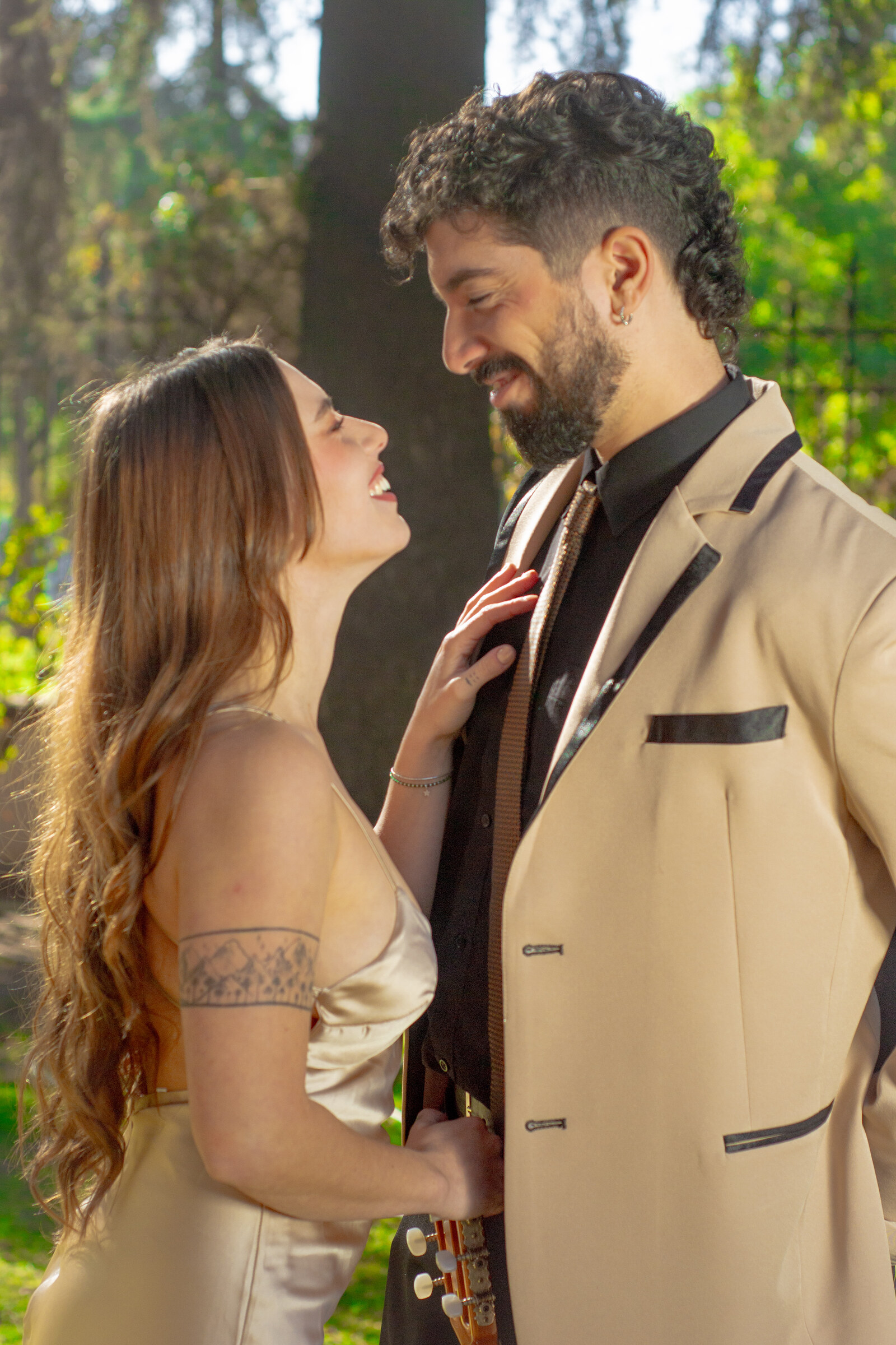 Dúo Amores de Chile compartiendo una sonrisa cómplice en un jardín soleado del Palacio Cousiño.